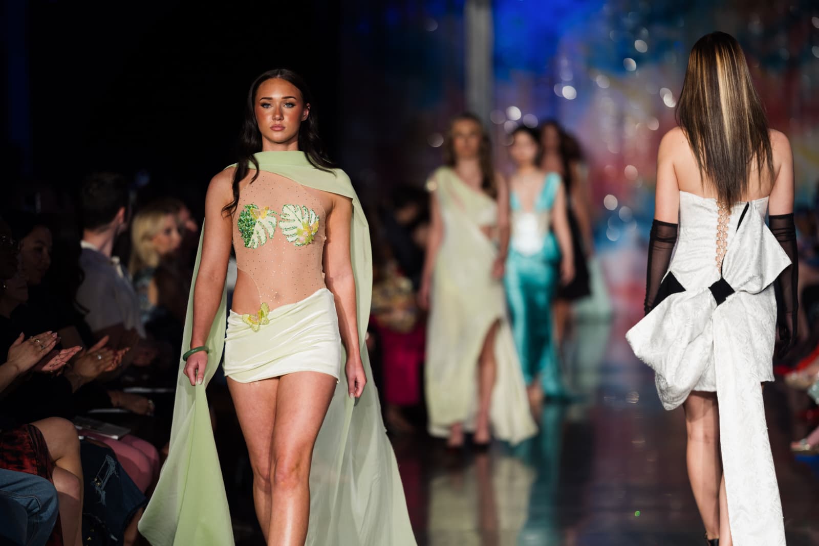 Model walking on a fashion runway wearing a green and white outfit with monstera floral details. HZUCHELLI LOOK 2